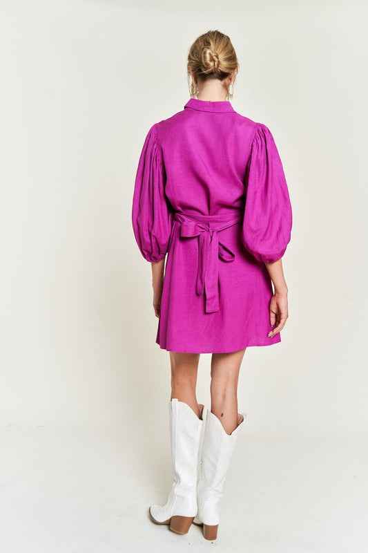 Back view of a vibrant pink plus size button down dress with puff sleeves and a waist tie